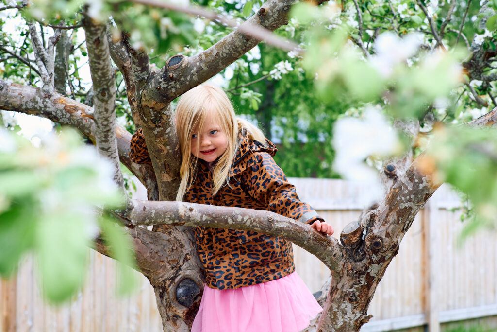 Flicka klättrar i träd